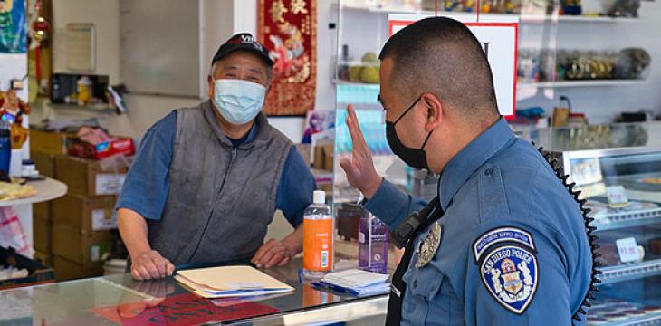 Police officer talking to man wearing mask.