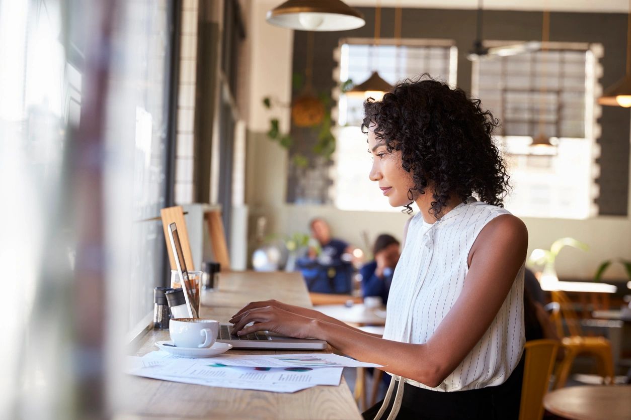 Woman working on laptop in cafe.