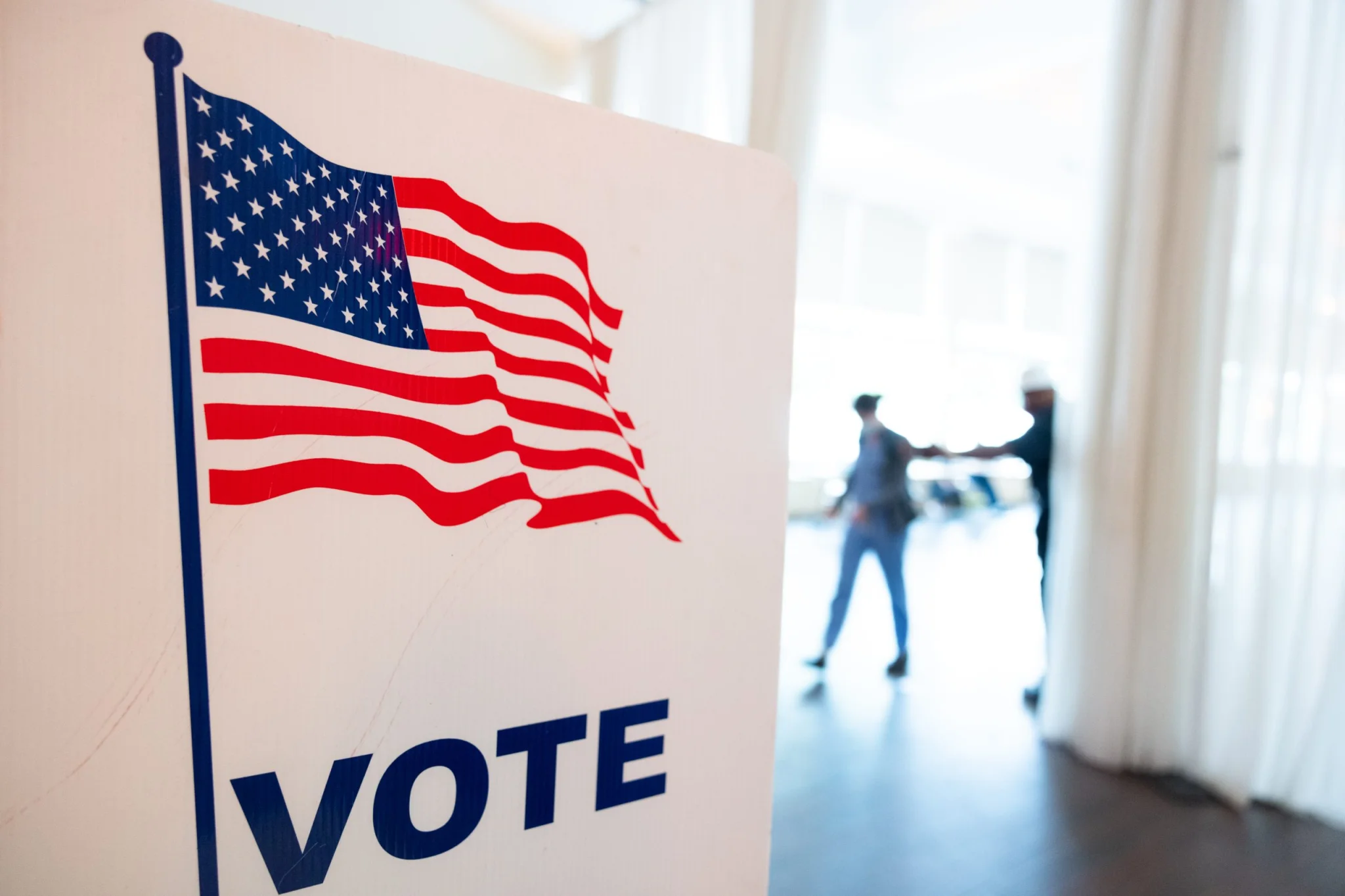 Vote sign with American flag in background.