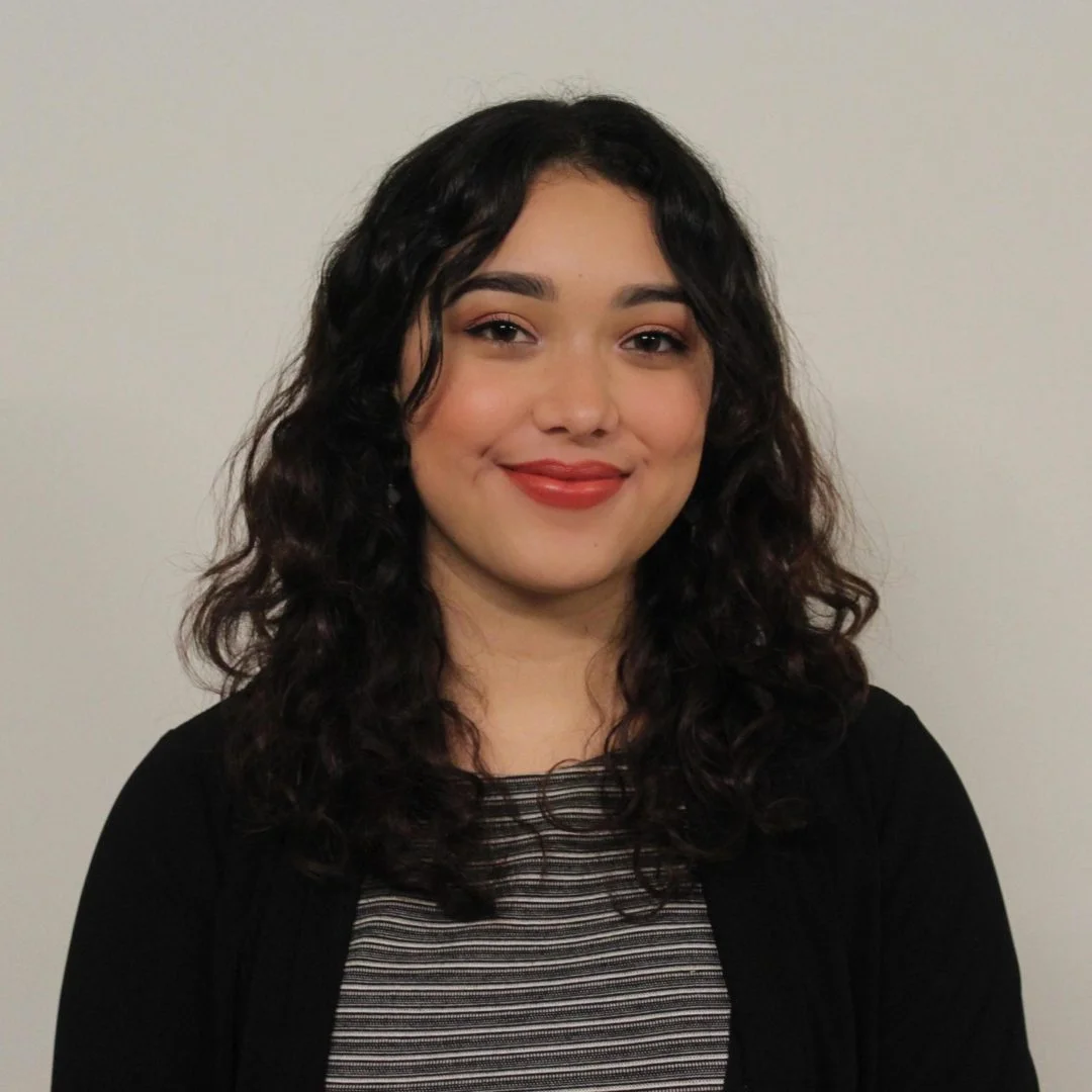 A woman with long curly hair smiling.